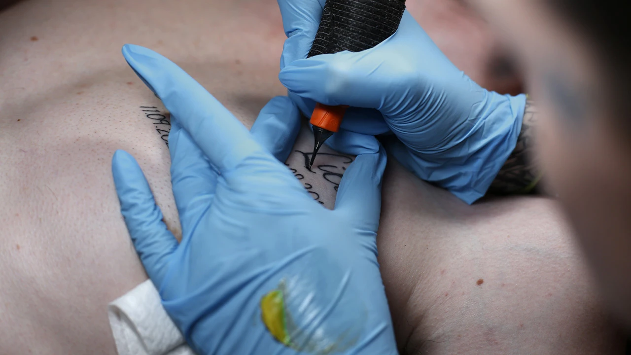 Tatouage écriture tattoo chez l en train de tatouer un prénom