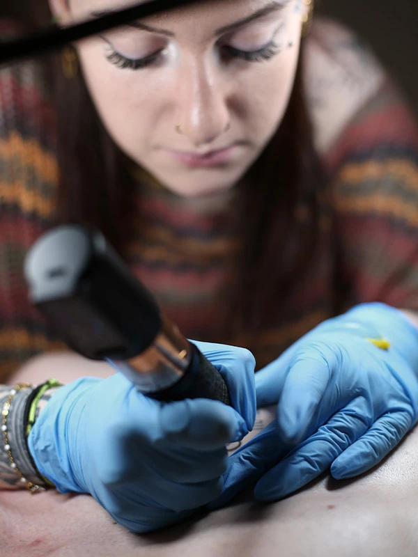 Léa - Tattoo chez L' tattoo chez l en train de tatouer un dos