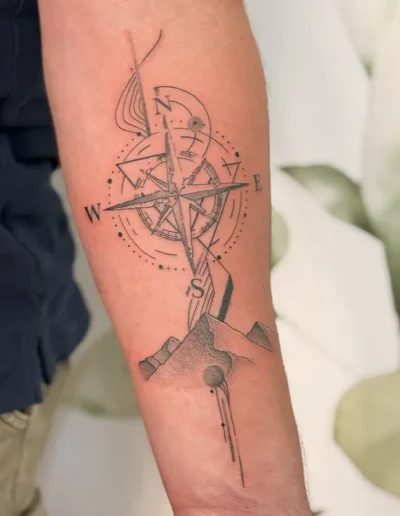 tatouage graphique fine line montagne et boussole sur l'avant-bras d'un homme - Tattoo chez L