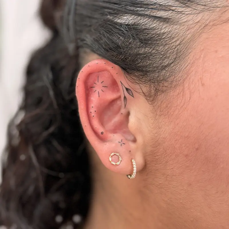 tatouage minimaliste ornemental sur l'oreille d'une femme