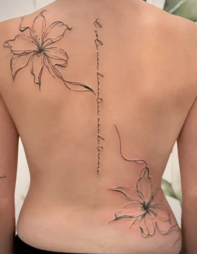 grand tatouage dans le dos d'une femme avec deux iris et une phrase en italien sur la colonne vertébrale - Tattoo chez L' (Vonnas, Ain)