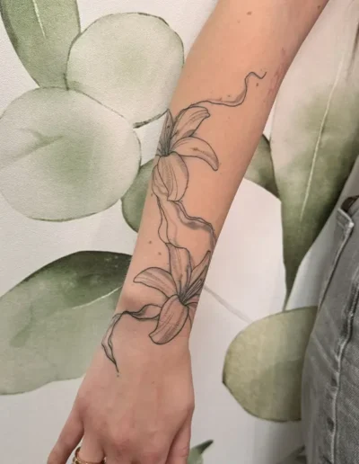 tatouage d'un lys le long de l'avant-bras d'une femme - Création Tattoo chez L' (Vonnas)