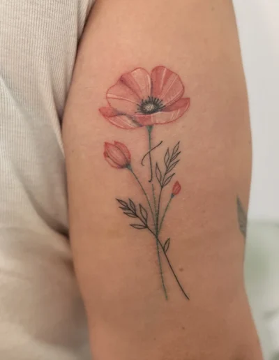 tatouage coquelicot rouge en style semi-réaliste à l'arrière du bras d'une femme